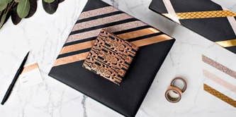 Combining presents by attaching a smaller gift to a larger one using Scotch® Double-Sided Tape
