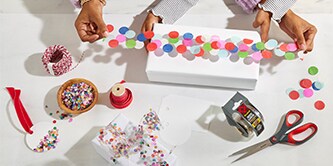 Wrapping a gift box with confetti tape made by sticking colourful confetti to Scotch® adhesive tape
