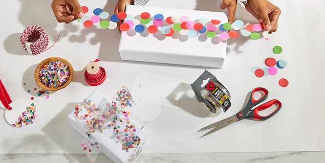 Woman and her daugther wrapping a gift box with confetti tape made by sticking colourful confetti to Scotch® Packaging Tape
