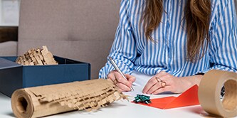  Woman carefully packing a gift and using Scotch™ Cushion Lock™ Protective Wrap
