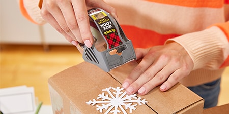 Sealing a holiday gift inside a parcel using Scotch® Box Lock™ Tape
