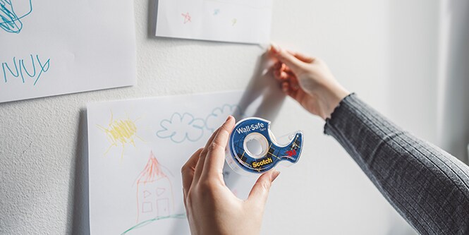 Hanging kids art on a wall using Scotch® Wall-Safe Tape
