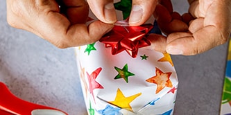 Using starry wrapping paper and finishing the gift wrap look with a ribbon star on top
