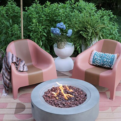 An outdoor patio setting with a painted deck, and a modern circular firepit in the middle.