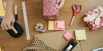 Woman wrapping a gift with Scotch™ Scissors, Scotch™ Tape Dispenser, and Scotch® Magic™ Tape Made with 66% Plant-based Adhesive
